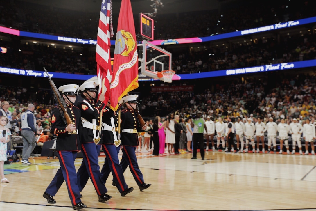 Marine Sgt. Amber Haddix, Sgt. Bree-Anna Perez, Sgt. Norma Gavilanes and Sgt. Carly Jones, all drill instructors at Marine Corps Recruit Depot Parris Island, South Carolina, march onto the Amalie Arena basketball court bearing rifles and the national ensign and Marine Corps colors for the national anthem at the National Collegiate Athletic Association Women’s Final Four Basketball Tournament Championship in Tampa, Florida, April 7, 2019. The tournament ran in conjunction with the 2019 Women’s Basketball Coaches Association Convention. The Marine Corps Recruiting Command has taken deliberate actions to increase diversity accessions and outreach by partnering with and attending engagement events such as WBCA, reprioritizing elements of advertising programs, increasing awareness of scholarships opportunities, and analyzing prospects and processing. The WBCA’s mission is to promote women’s basketball by unifying coaches at all levels to develop a reputable identity for the sport and to foster and promote the development of the game of basketball as a sport for women and girls. (U.S. Marine Corps photo by Cpl. Naomi May)