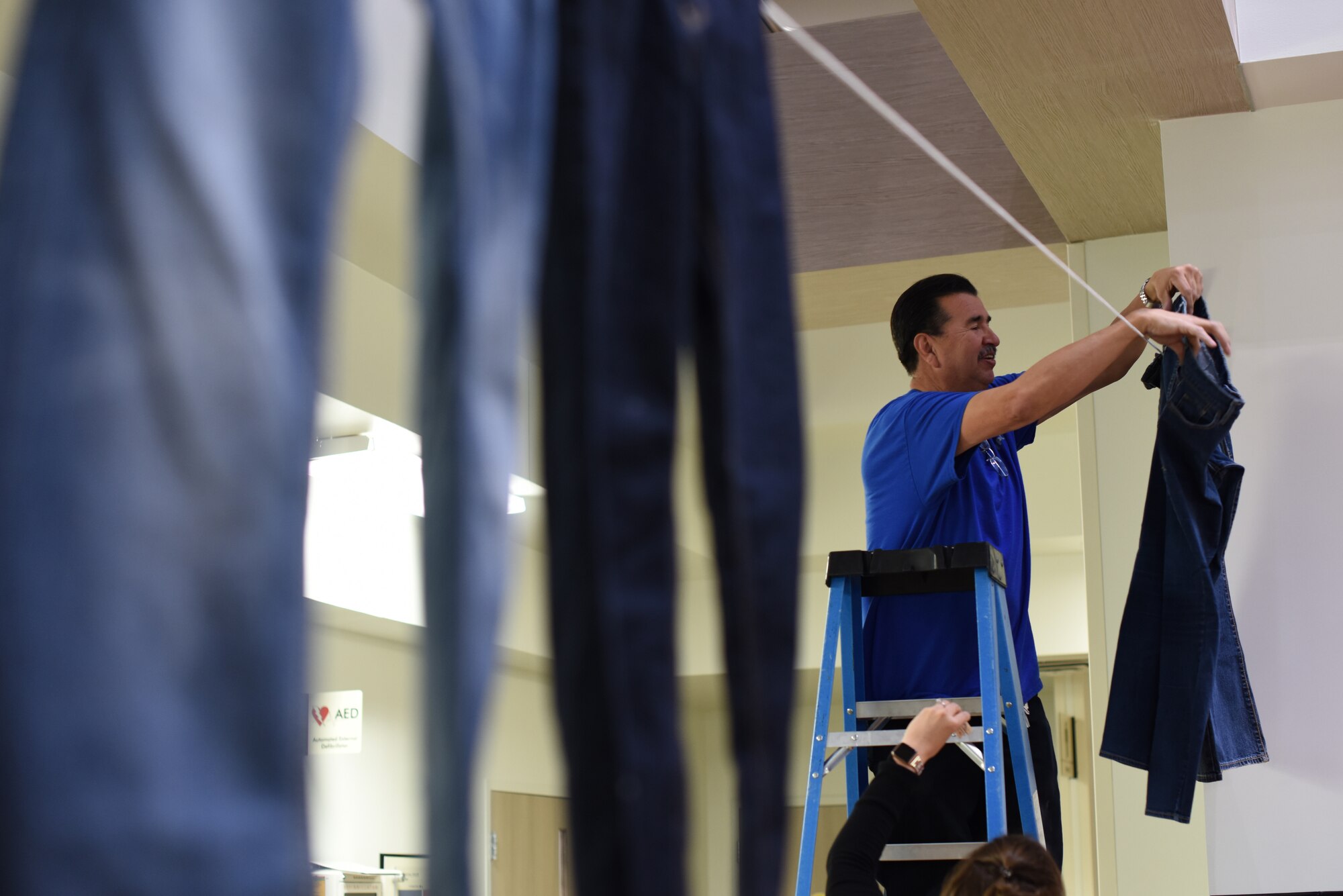 Alfonso Padilla, 377th Medical Group facilities, hangs jeans at the 377th MDG April 8, 2019. Over 40 pairs of jeans were hung up around Kirtland Air Force Base to raise awareness for sexual assault prevention month, and to celebrate Denim Day. (U.S. Air Force photo by Senior Airman Eli Chevalier)