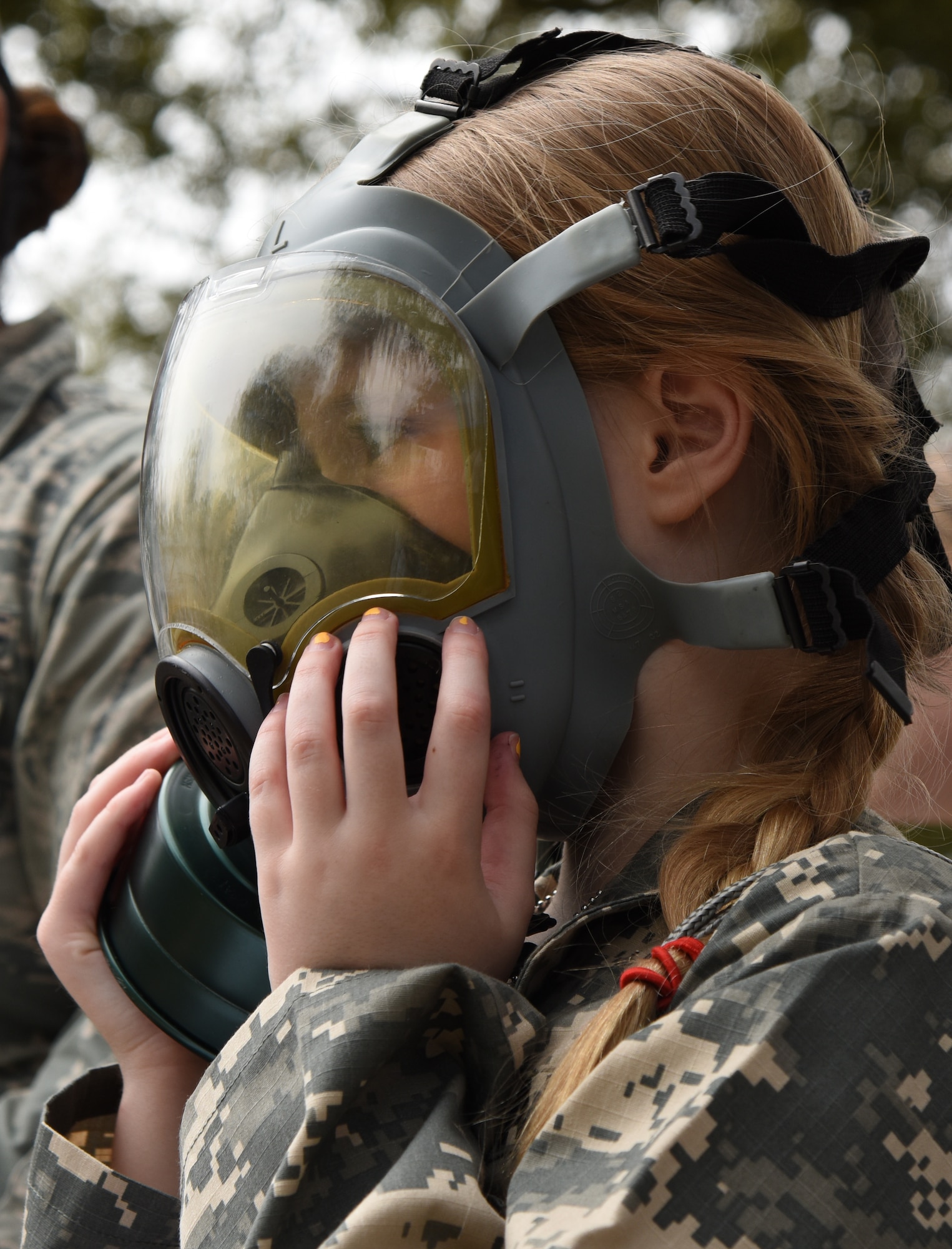 Emily Quigley, daughter of U.S. Air Force Col. Marcia Quigley, 81st Mission Support Group commander, tries on a gas mask during Operation Hero at Keesler Air Force Base, Mississippi, April 6, 2019. The event, hosted by the Airman and Family Readiness Center in recognition of the Month of the Military Child, gave military children a glimpse into the lives of deployed military members. Children received Operation Hero dog tags and t-shirts as they made their way through the mock deployment line as well as the opportunity to experience medical triage demonstrations, gas mask training and have their faces painted. (U.S. Air Force photo by Kemberly Groue)