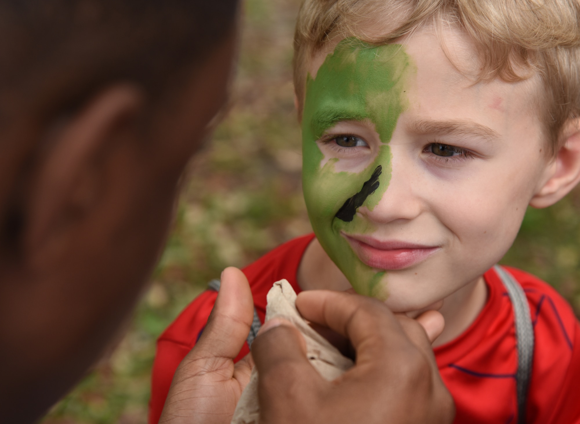 U.S. Air Force Airman Basic Lavelle Hagan, 335th Training Squadron student, applies "war paint" on Channing Harrigan, son of Tech. Sgt. Lindzi Rodrigue, 81st Diagnostic and Therapeutics Squadron unit program coordinator, during Operation Hero at Keesler Air Force Base, Mississippi, April 6, 2019. The event, hosted by the Airman and Family Readiness Center in recognition of the Month of the Military Child, gave military children a glimpse into the lives of deployed military members. Children received Operation Hero dog tags and t-shirts as they made their way through the mock deployment line as well as the opportunity to experience medical triage demonstrations, gas mask training and have their faces painted. (U.S. Air Force photo by Kemberly Groue)