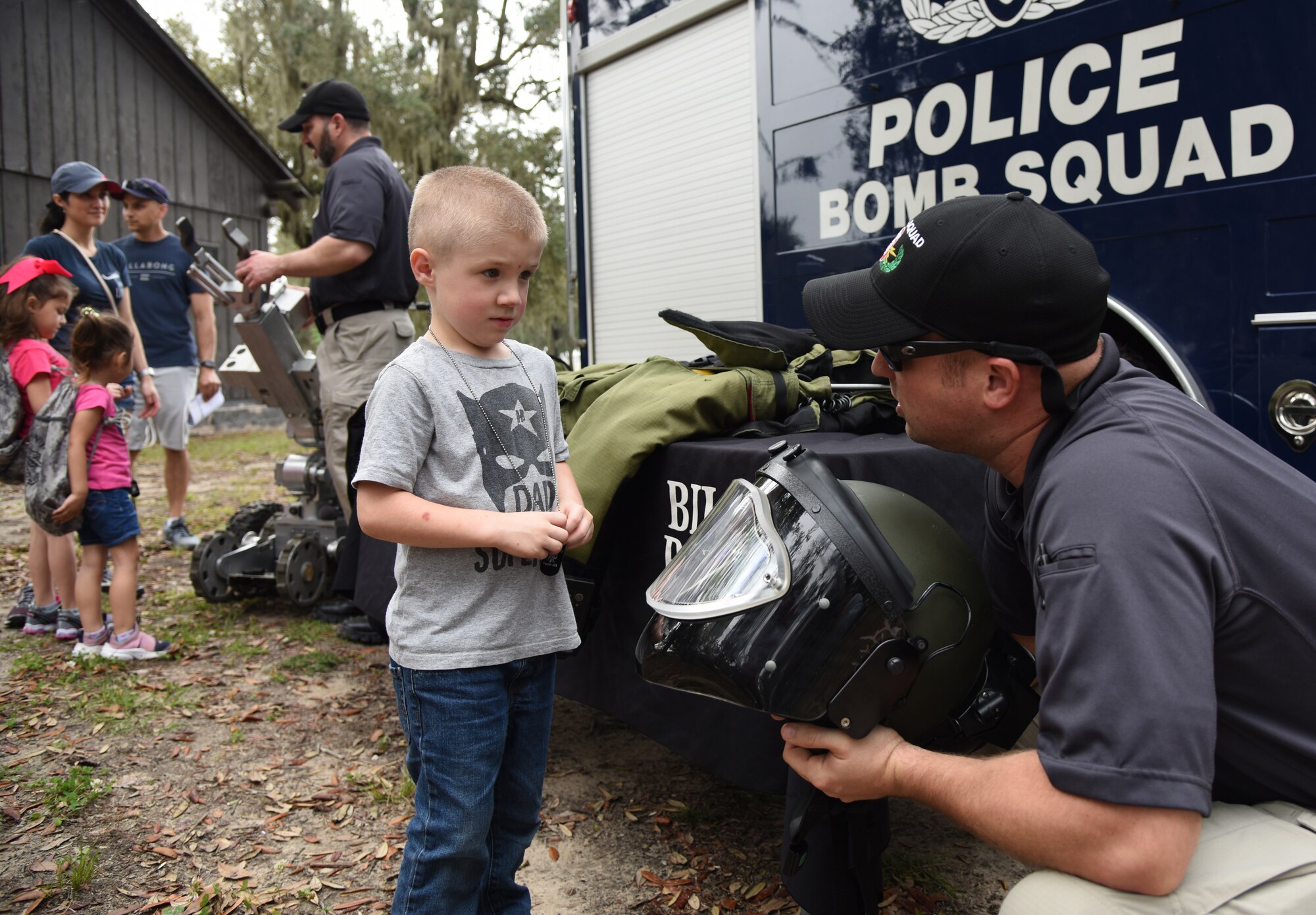 Sergeant Matthew Boone, Biloxi Bomb Squad technician, shows a protective helmet worn by his team members to Mason Taykowski, son of U.S. Air Force Tech. Sgt. Justin Taykowski, 338th Training Squadron instructor, during Operation Hero at Keesler Air Force Base, Mississippi, April 6, 2019. The event, hosted by the Airman and Family Readiness Center in recognition of the Month of the Military Child, gave military children a glimpse into the lives of deployed military members. Children received Operation Hero dog tags and t-shirts as they made their way through the mock deployment line as well as the opportunity to experience medical triage demonstrations, gas mask training and have their faces painted. (U.S. Air Force photo by Kemberly Groue)
