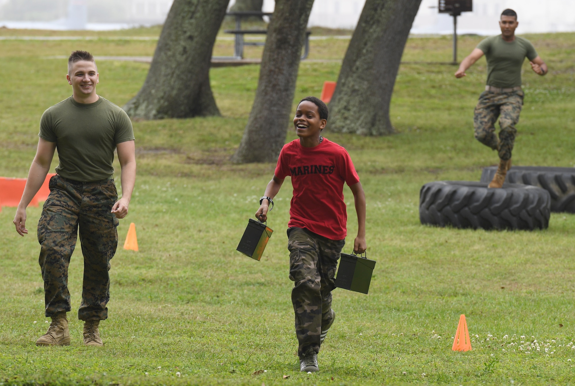 Carlos Cadet, Jr., son of U.S. Marine Corps Cpl. Jalisa Cadet, Keesler Marine Detachment administration clerk, runs through an obstacle course as he is escorted by Cpl. Davis Steiner, Keesler MARDET instructor, and followed by Pfc. Janathan Singh, Keesler MARDET student, during Operation Hero at Keesler Air Force Base, Mississippi, April 6, 2019. The event, hosted by the Airman and Family Readiness Center in recognition of the Month of the Military Child, gave military children a glimpse into the lives of deployed military members. Children received Operation Hero dog tags and t-shirts as they made their way through the mock deployment line as well as the opportunity to experience medical triage demonstrations, gas mask training and have their faces painted. (U.S. Air Force photo by Kemberly Groue)