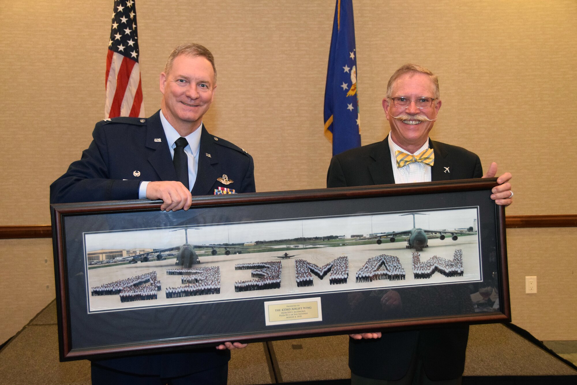 Col. Terry McClain, 433rd Airlift Wing commander, is presented with a vintage 433rd Military Airlift Wing panoramic photo from 1991 by Steve Richmond, an honorary commander alumni and president of Pizza Hut of San Antonio, April 6, 2019 at a northwest San Antonio hotel. Seventeen honorary commanders were inducted at the annual event.
