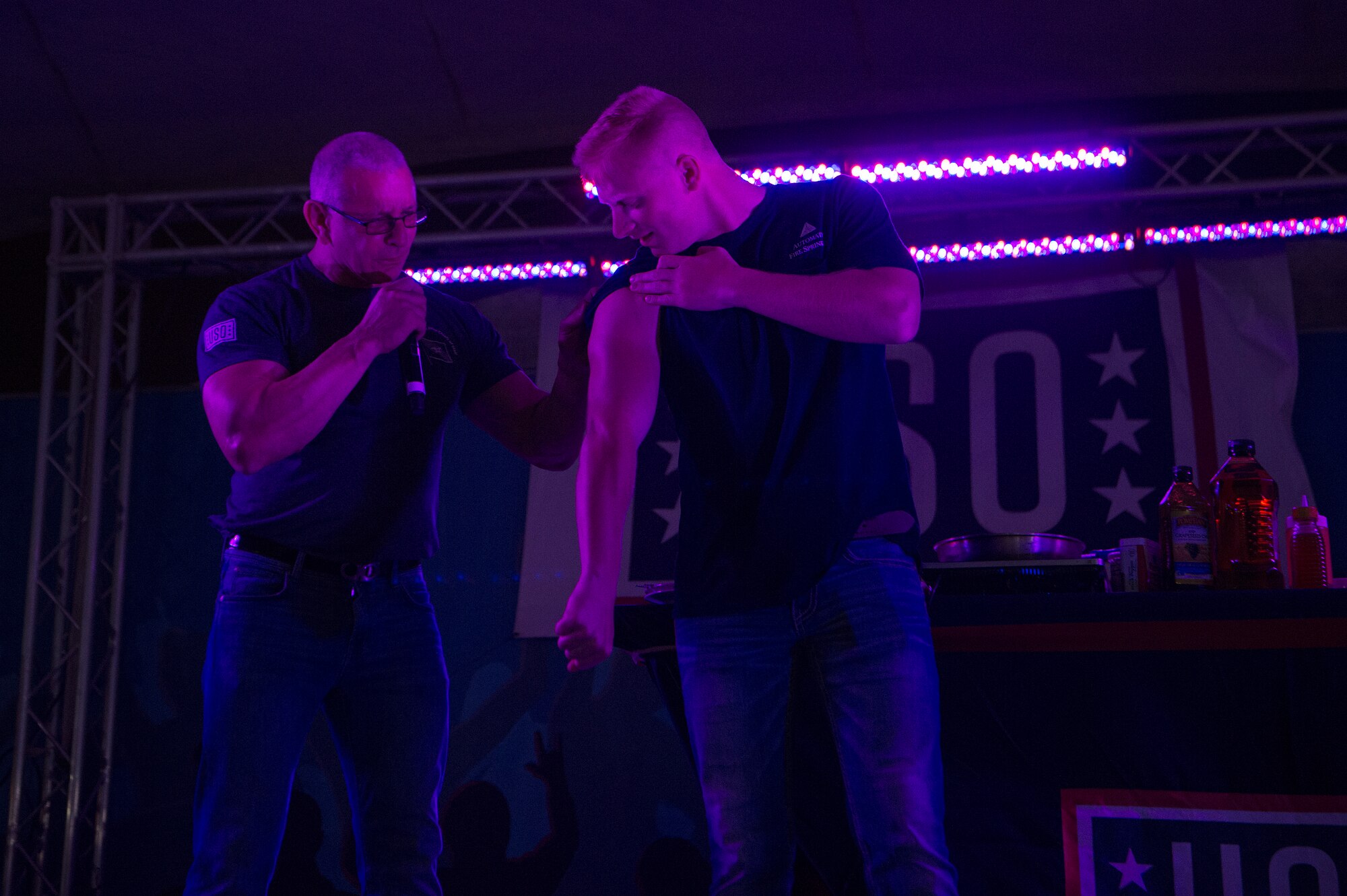Chef Robert Irvine challenges a service member to complete push-ups faster than he can cook a meal during the United Service Organizations (USO) tour April 1, 2019, at Al Udeid Air Base, Qatar. Irvine shared the stage with music performers and professional athletes during the show.