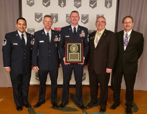 U.S. Air Force Master Sgt. Stephen Sanabria, Senior Master Sgt. Lance Berentson and Chief Master Sgt. William Taylor, all 100th Civil Engineer Squadron Fire Department, pose for a photo with their Accredited Agency Award plaque along with Steve Dirkson, Fargo Fire Department fire chief, North Dakota, and Mike Higgins, deputy fire chief of Columbus Fire Department, Georgia, and peer assessment team lead,  after officially becoming accredited by the Commission on Fire Accreditation International at the Center for Public Safety and Excellence conference, at Orange Grove, Calif., March 14, 2019. The RAF Mildenhall Fire Department is the first Department of Defense fire station in the United Kingdom and only the second in U.S. Air Forces in Europe to receive the accreditation. (Courtesy photo)