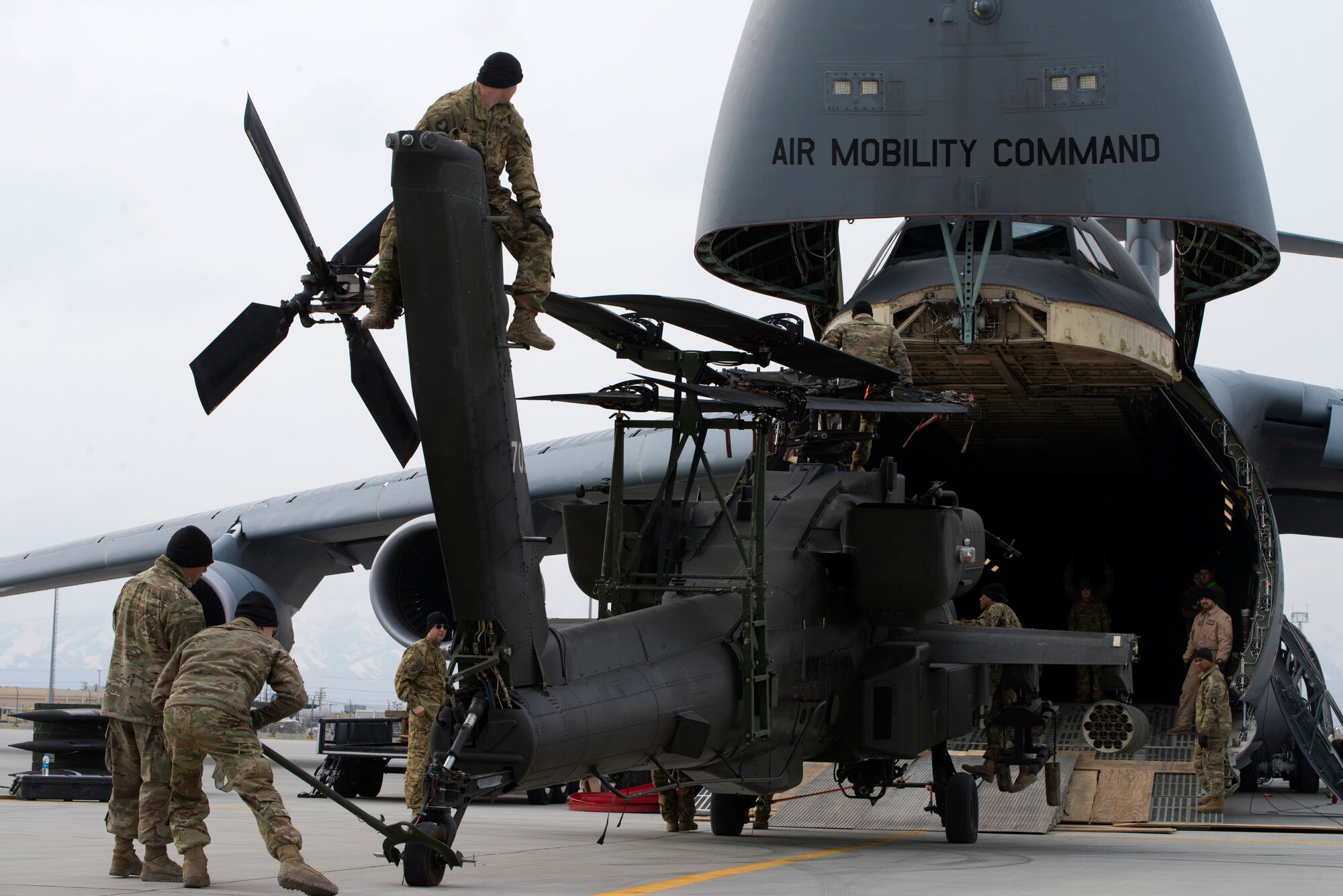 Airmen, Soldiers, and personnel prepare to load Apache Helicopters into a C-5 at Bagram Airfield, Afghanistan, on Feb. 20, 2019. Troops must work together to ensure the Apache will ‘clear’ the C-5 during the loading process. (U.S. Air Force photo by Senior Airman Jean-Paul Arnaud-Marquez)
