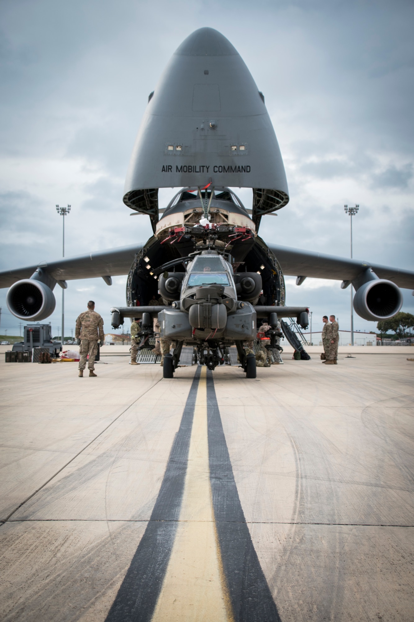 Soldiers assigned to the 1st Armored Division and 1109th Theater Aviation Sustainment Maintenance Group load an AH-60 Apache helicopter onto a C-5 aircraft during Intermodal operations. Intermodal operations combine sea and air transportation to reduce cargo handling, improve security, minimize damage and allow quicker transportation. (U.S. Navy photo by Mass Communication Specialist 1st Class Benjamin A. Lewis)