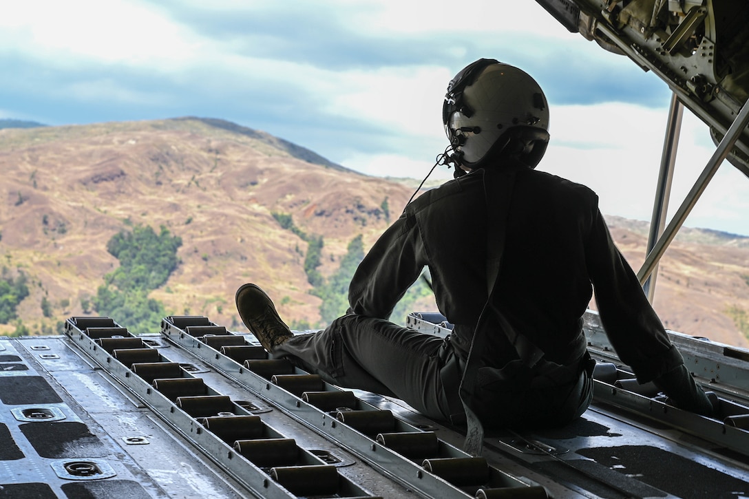 A Marine looks out from the back of an aircraft.