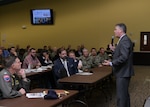 Mike Cannon (seated, second from left in first row), DLA Disposition Services director, and Kathy Atkins-Nunez (seated, second from left in second row, DLA Disposition Services’ South-East Region director, listen as Thomas W. Harker, assistant secretary of the Navy for financial management and comptroller, presents data findings from a recent Navy full financial statement audit.