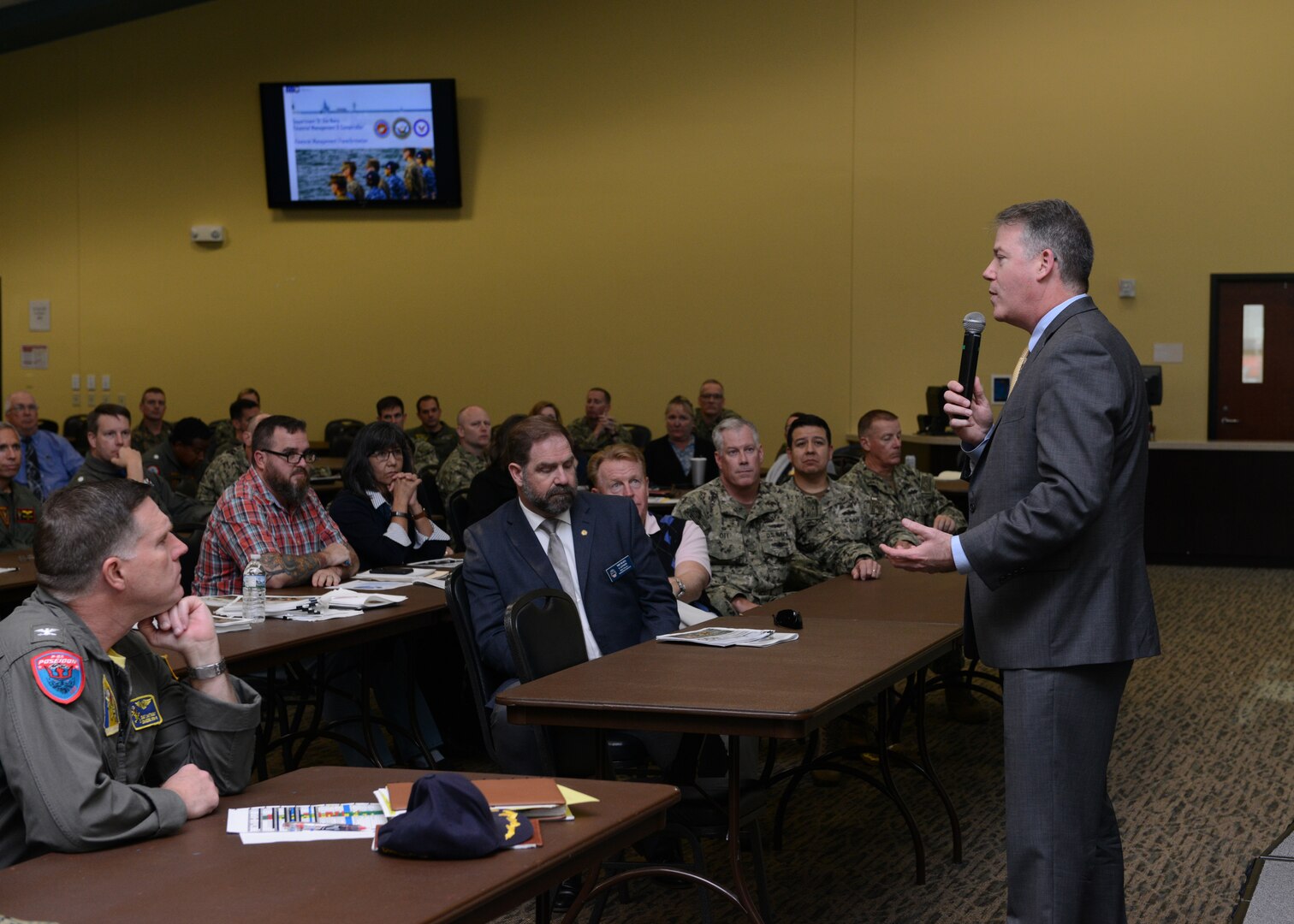 Mike Cannon (seated, second from left in first row), DLA Disposition Services director, and Kathy Atkins-Nunez (seated, second from left in second row, DLA Disposition Services’ South-East Region director, listen as Thomas W. Harker, assistant secretary of the Navy for financial management and comptroller, presents data findings from a recent Navy full financial statement audit.