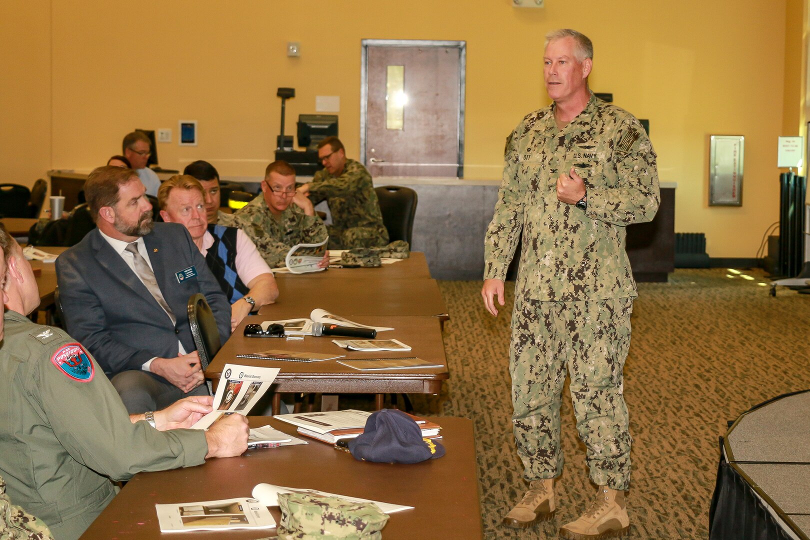 Mike Cannon (seated, second from left in first row), DLA Disposition Services director, listens as Navy Capt. Matthew N. Ott III, commanding officer of the Naval Supply System Command’s Fleet Logistics Center at Jacksonville, addresses the audience