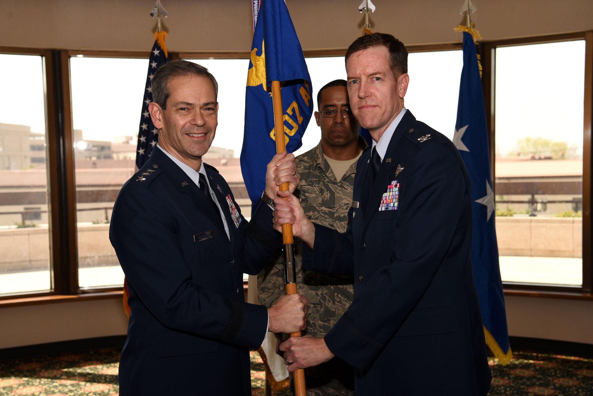 U.S. Air Force Lt. Gen. Kenneth S. Wilsbach, Seventh Air Force commander, passes the 607th Air Operations Center guidon to Col. Christopher Russell, incoming commander, during an assumption of command ceremony at Osan Air Base, Republic of Korea, April 5, 2019. The passing of the guidon symbolizes a change of leadership and responsibility. (U.S. Air Force photo by Staff Sgt. Kelsey Tucker)