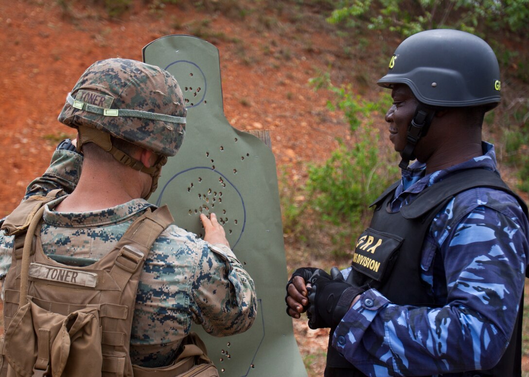 A  U.S. Marine with Special Purpose Marine Air-Ground Task Force-Crisis Response-Africa 19.1, Marine Forces Europe and Africa, advises a member of the Ghanaian customs division on his shot grouping after a live-fire range during a theater-security cooperation event in Asutsuare, Ghana, March 18, 2019. SPMAGTF-CR-AF is deployed to conduct crisis-response and theater-security operations in Africa and promote regional stability by conducting military-to-military training exercises throughout Europe and Africa. (U.S. Marine Corps photo by 1st Lt. Taylor Cox)