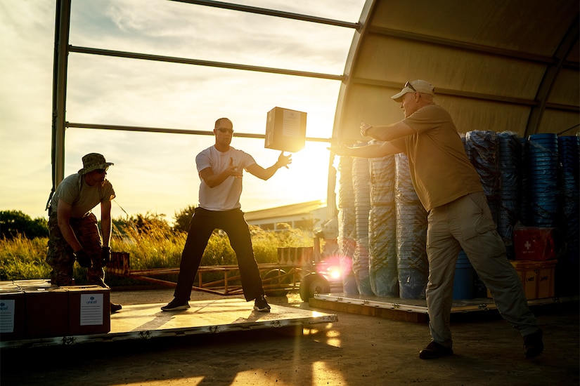 A man throws a box to another man.