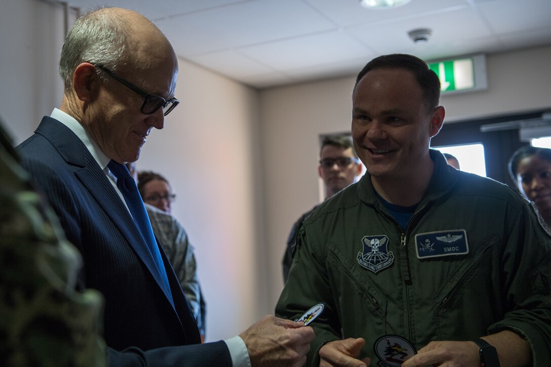 Lt. Col. Jarred “SMOC” Prier (right), Bomber Task Force Operations Group commander deployed from Barksdale Air Force Base, La., gives U.S. Ambassador to the U.K. Robert Wood Johnson (left), a 20th Bomb Squadron patch at RAF Fairford, England, March 29, 2019. Johnson toured the operations building to get information on how the BTF OG was operating on base for the BTF. (U.S. Air Force photo by Airman 1st Class Tessa B. Corrick)