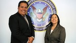 A man and a woman stand in front of Agency seal.