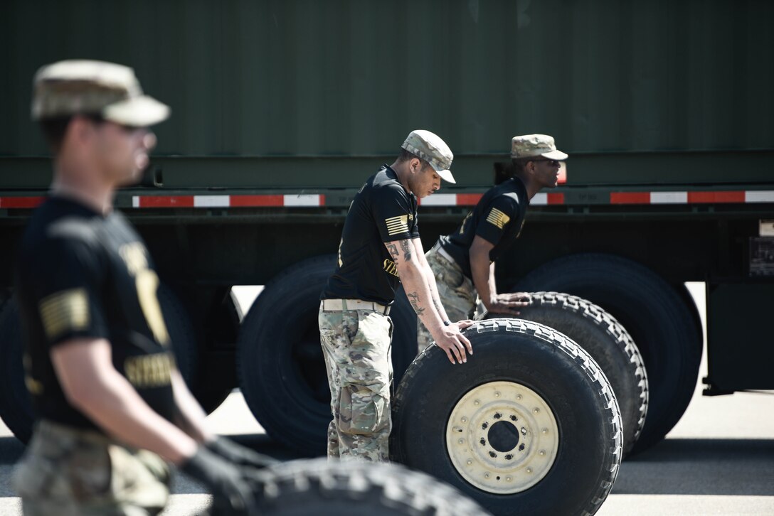 U.S. Army Soldiers assigned to the 368th Seaport Operations Company, 11th Transportation Battalion, 7th Trans. Brigade (Expeditionary), steady the tires for the Soldiers competing for the fastest tire change at Joint Expeditionary Base Little Creek-Fort Story, Virginia, March 29, 2019. The Soldiers from the company are tasked with judging the truck rodeo competition since they were the creators of the concept. (U.S. Army photo by Spc. Travis Teate)