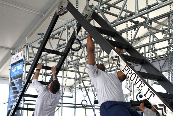 Two members of the Air Force Services Activity demonstrate one of nine stations on an Alpha Warrior Battle Rig during Industry Day April 9, 2019, on Joint Base San Antonio-Lackland, Texas.