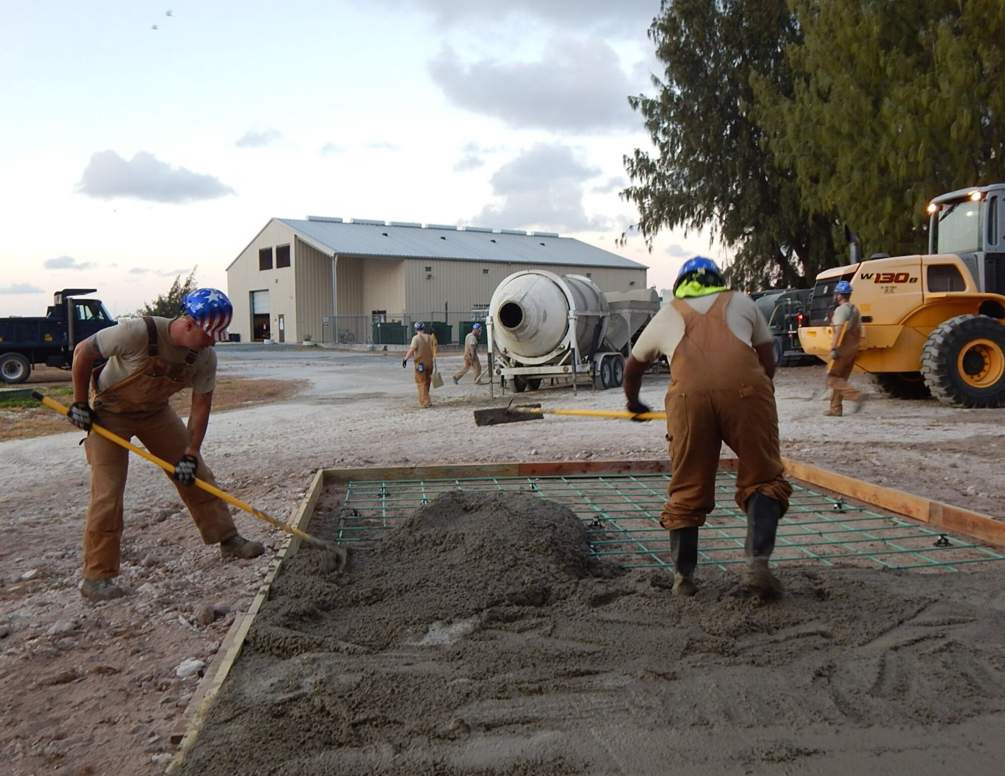 U.S. Air Force Staff Sgt. Tyler Charles, 611th Civil Engineer Squadron pavements and equipment noncommissioned officer in charge, and U.S. Air Force Tech. Sgt. Donald Scott, 611th CES sub-activity management plan manager, rake concrete at Wake Island, February 2018.  The engineers were building a concrete ramp for one of the Missile Defense Agency’s facilities.