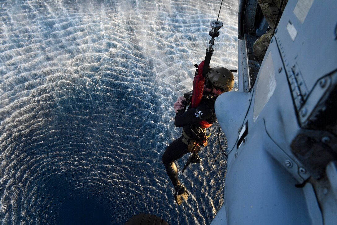 A sailor is lowered into the ocean.