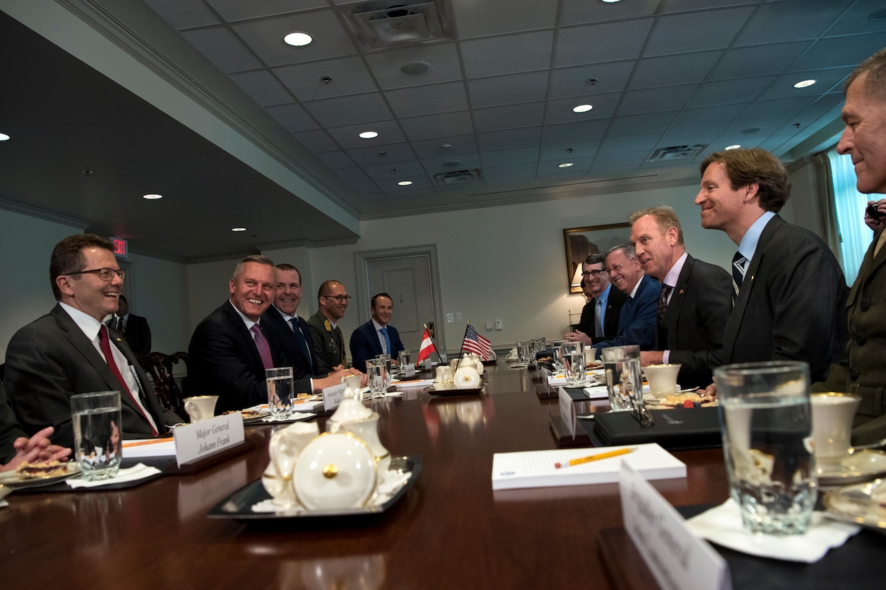 Acting Defense Secretary Patrick M. Shanahan sits at at table with a group of people.