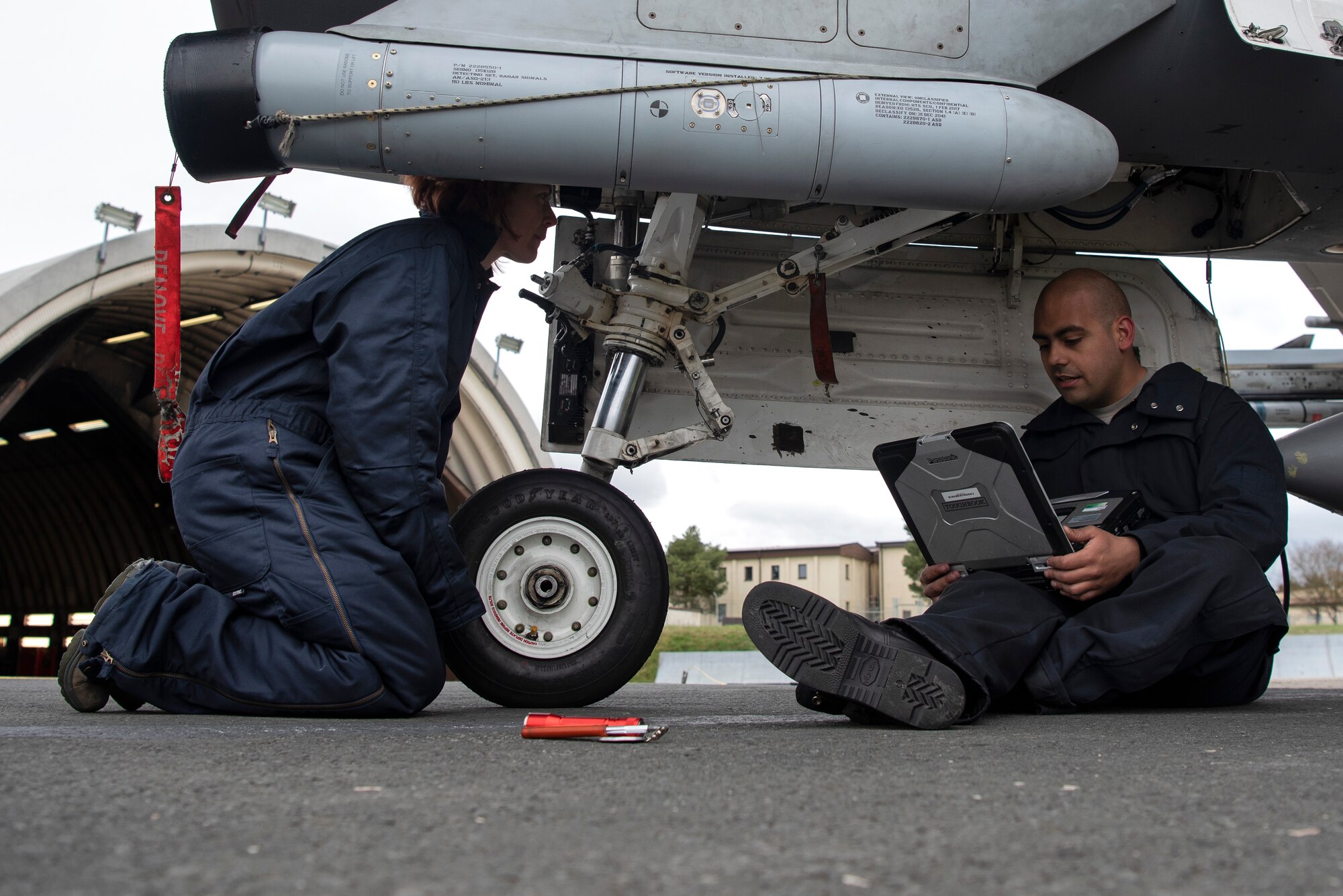 U.S. Air Force Staff Sgt. Stephanie Gillie, 52nd Security Forces Squadron investigator, left, observes Senior Airman Jose Pagan, 52nd Aircraft Maintenance Squadron assistant dedicated crew chief, right, as he inspects F-16 Fighting Falcon landing gear at Spangdahlem Air Base, Germany, April 3, 2019. Gillie, who had never been on a flightline before, volunteered for the 52nd AMXS Crew Chief for a Day program. She learned how inspections are performed and how to prepare an aircraft for launch. (U.S. Air Force photo by Airman 1st Class Valerie Seelye)