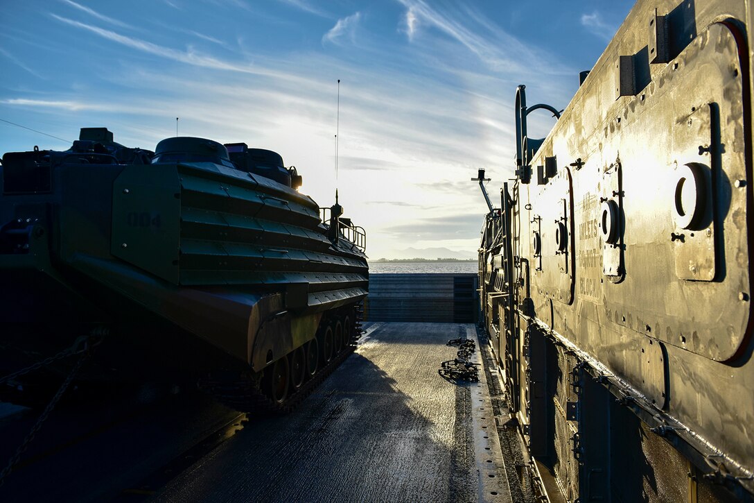 A Navy landing craft transports a vehicle.
