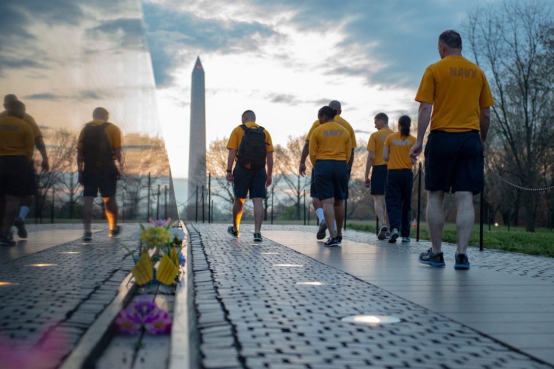 Sailors walk along a portion of a memorial.