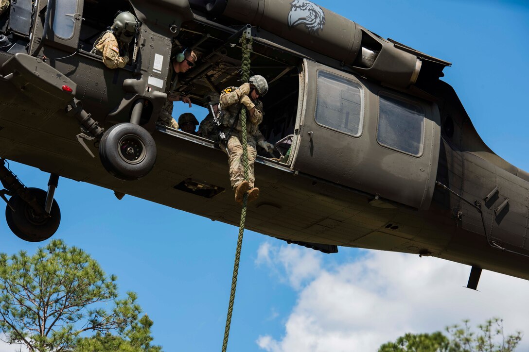 An airman slides down a rope from a helicopter.
