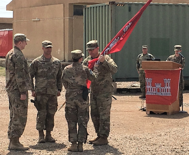 U.S. Army Corps of Engineers Task Force Essayons (TFE) Commander Col. Riely hands the flag to Capt. Andrea Taylor during a Change of Command ceremony at Camp Taji, Iraq, April 6, 2019. Taylor assumed command of the TFE Headquarters Detachment from Capt. Joe Marut (2nd from left) during the ceremony. Also pictured is TFE 1st Sergeant Robert Polsunas.