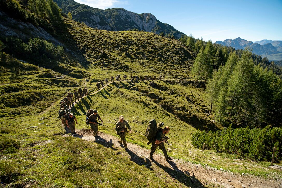 Soldiers climb a mountain.