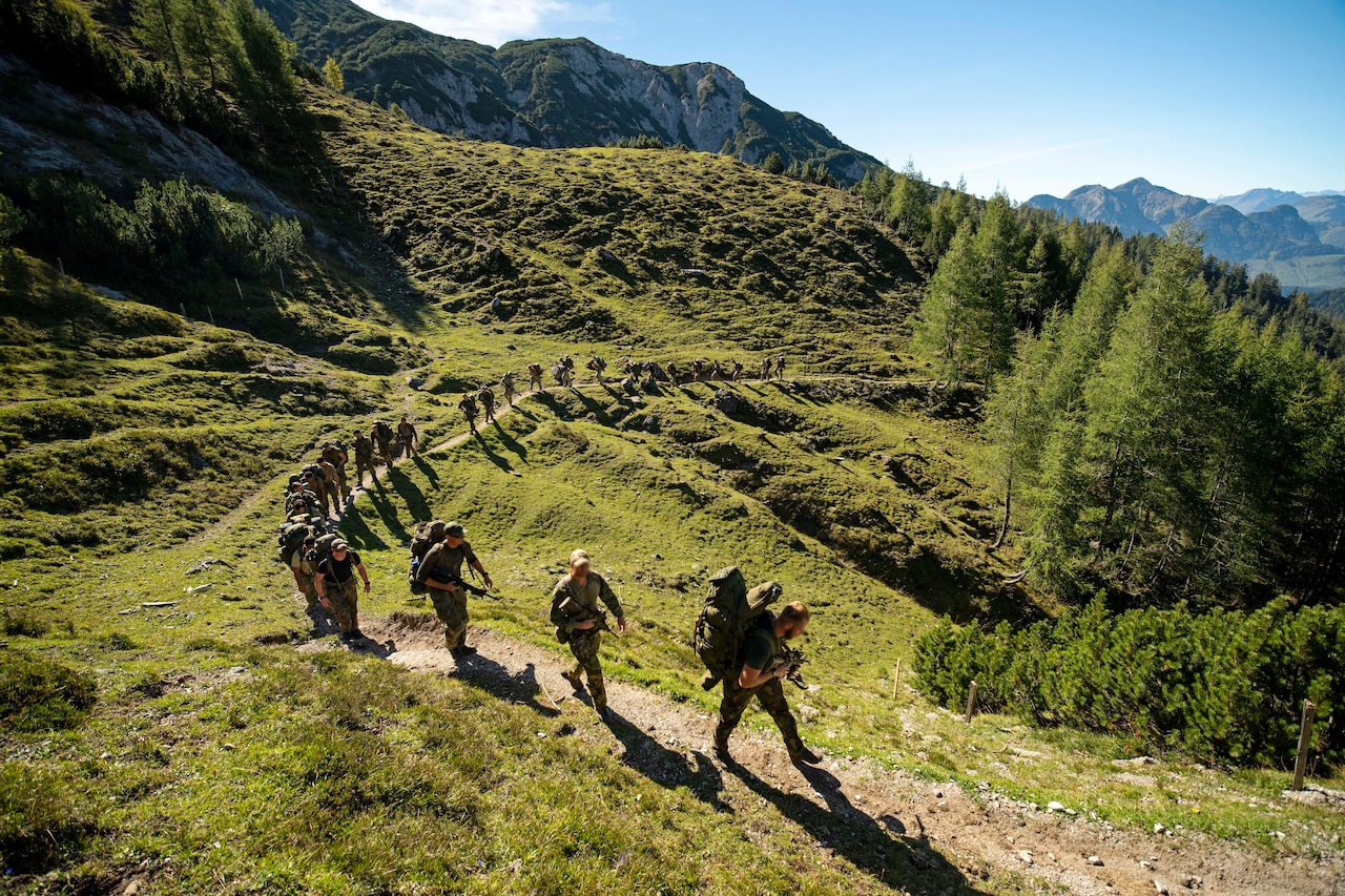 Soldiers climb a mountain.