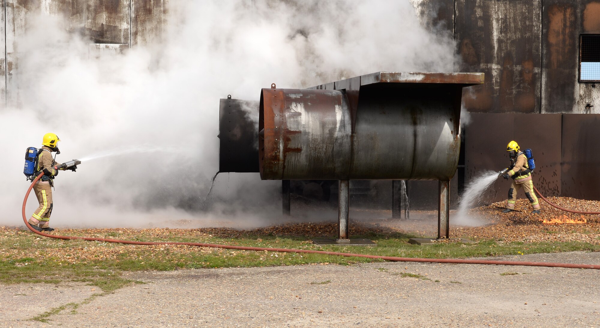 Royal Air Force firefighters from RAF Marham, Norfolk, extinguish the flames on a mock aircraft fire at the training area on RAF Mildenhall, England, April 5, 2019. The British fire crew visited the base to gain experience on the live fire trainer. With the arrival of the F-35 and the regeneration at RAF Marham, their training facilities are under renovation and the visit served to provide vital training for the RAF firefighters, and aid in continuing to build vital working relationships between RAF Mildenhall and neighboring fire departments. (U.S. Air Force photo by Karen Abeyasekere)