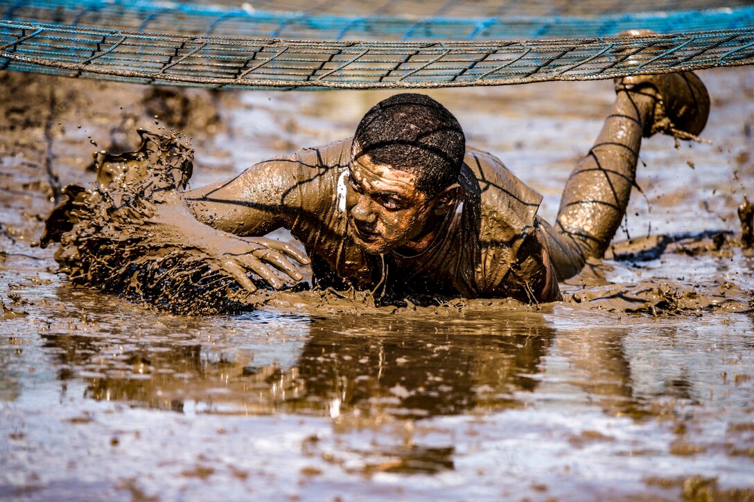 A man crawls through the mud.