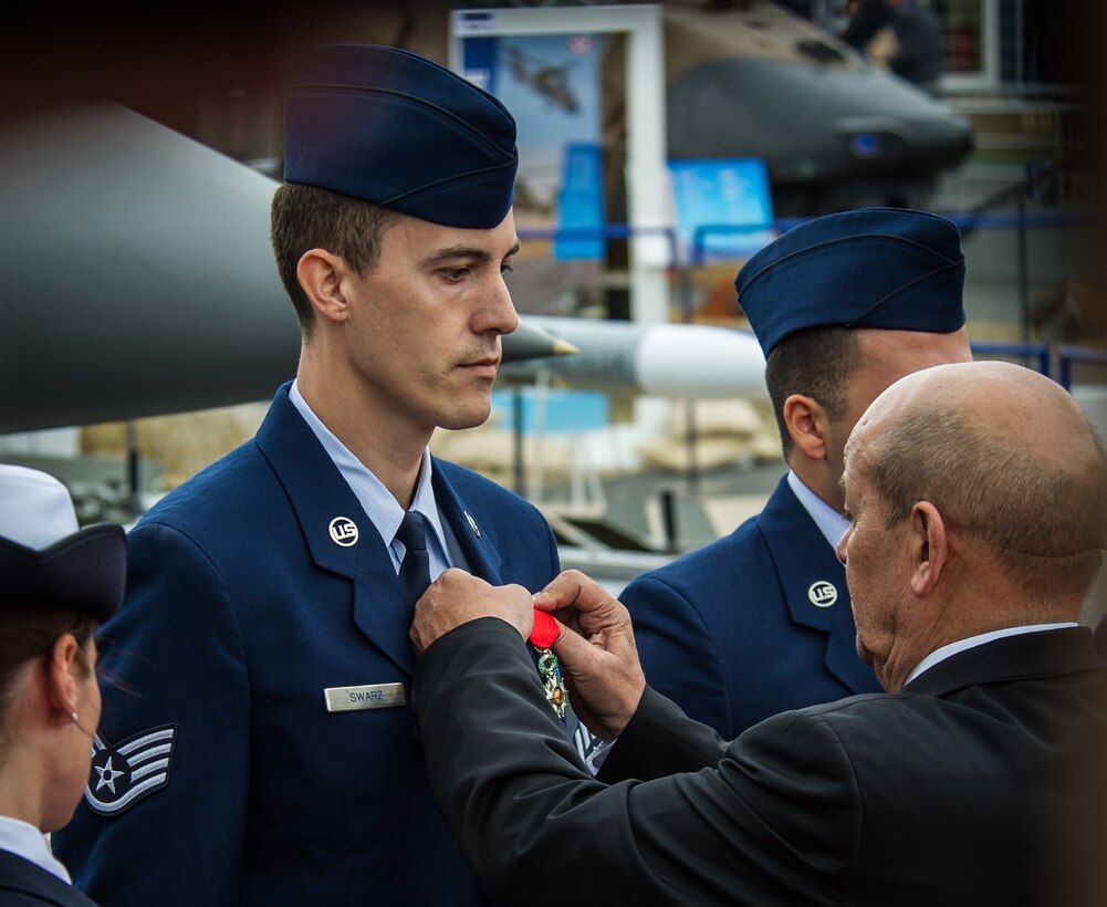 French Minister of Defence Jean Yves Le Drian pins the French Legion of Honor Medal on Staff Sgt. Greggory Swarz at Le Bourget Airport during the International Paris Air Show, June 15, 2015. Swarz was recognized for his heroic actions on Jan. 26, 2015, when he saved the lives of three French airmen after a Hellenic air force F-16 Fighting Falcon crashed into the parking ramp at Los Llanos Air Base, Spain, during Tactical Leadership Program 15-1. (U.S. Air Force photo/ Tech. Sgt. Ryan Crane)