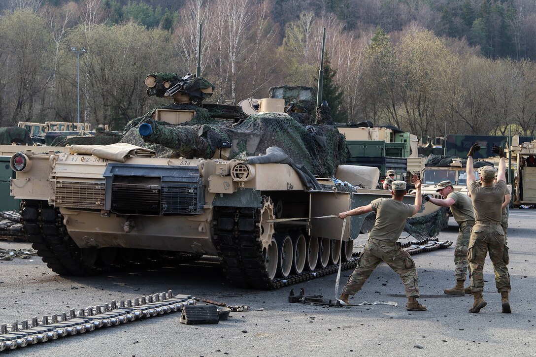 Soldiers perform maintenance on tanks.