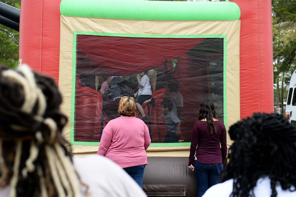 Caregivers watch over kids playing in the bouncy castle during the Youth Center’s Month of the Military Child kickoff, April 5, 2019, on Columbus Air Force Base, Miss. One major theme for the month of April is "Purple Up" , which is used as a way to show support and thank military youth for their strength and spirit. (U.S. Air Force photo by Airman Hannah Bean)