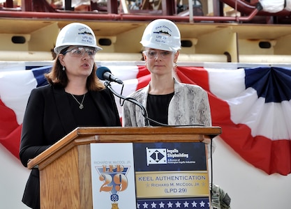 Shana McCool (left) and Kate Oja, ship sponsors of the future USS Richard M. McCool Jr. (LPD 29), speak about their grandfather during the keel authentication ceremony for the ship at Huntington Ingalls Industries Pascagoula shipyard April 12.