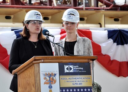 Shana McCool (left) and Kate Oja, ship sponsors of the future USS Richard M. McCool Jr. (LPD 29), speak about their grandfather during the keel authentication ceremony for the ship at Huntington Ingalls Industries Pascagoula shipyard April 12.