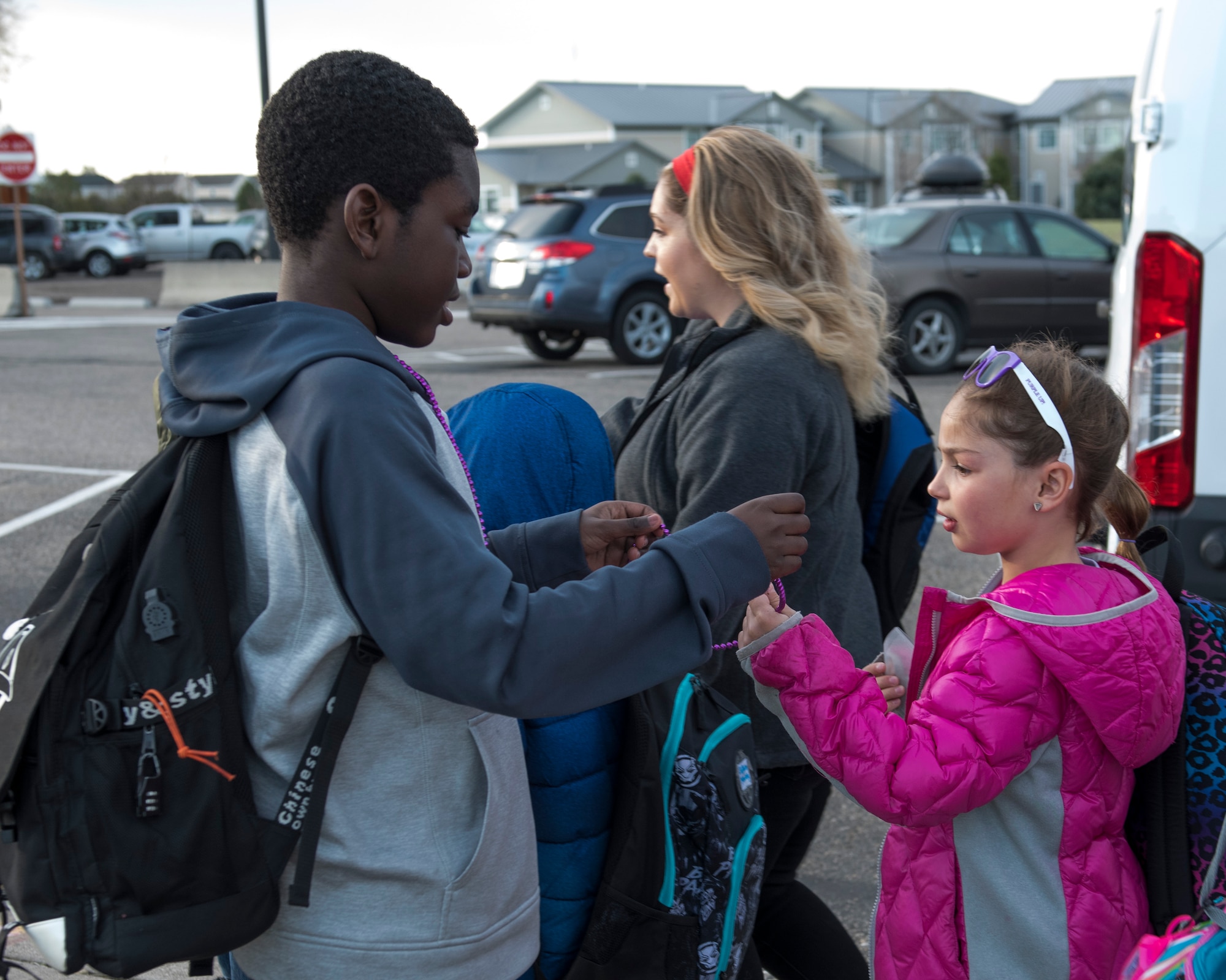 Children receive purple necklaces in celebration of Month of the Military Child April 12, 2019, at Mountain Home Air Force Base, Idaho. Personnel from MHAFB cheered on Gunfighter kids before school. (U.S. Air Force Photo by Airman 1st Class Hailey Bivens)