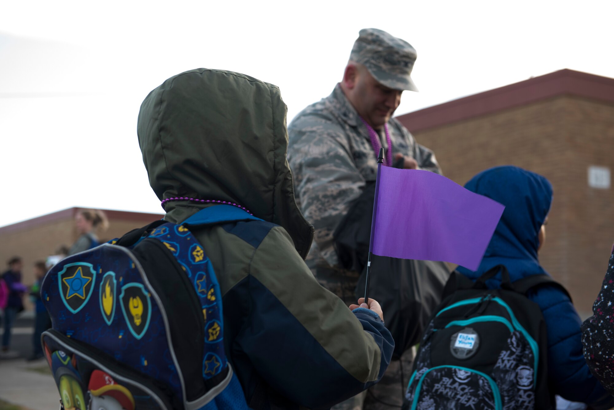 Children receive purple flags before school April 12, 2019, at Mountain Home Air Force Base, Idaho. Purple is the color used to represent the Month of the Military Child. (U.S. Air Force Photo by Airman 1st Class Hailey Bivens)