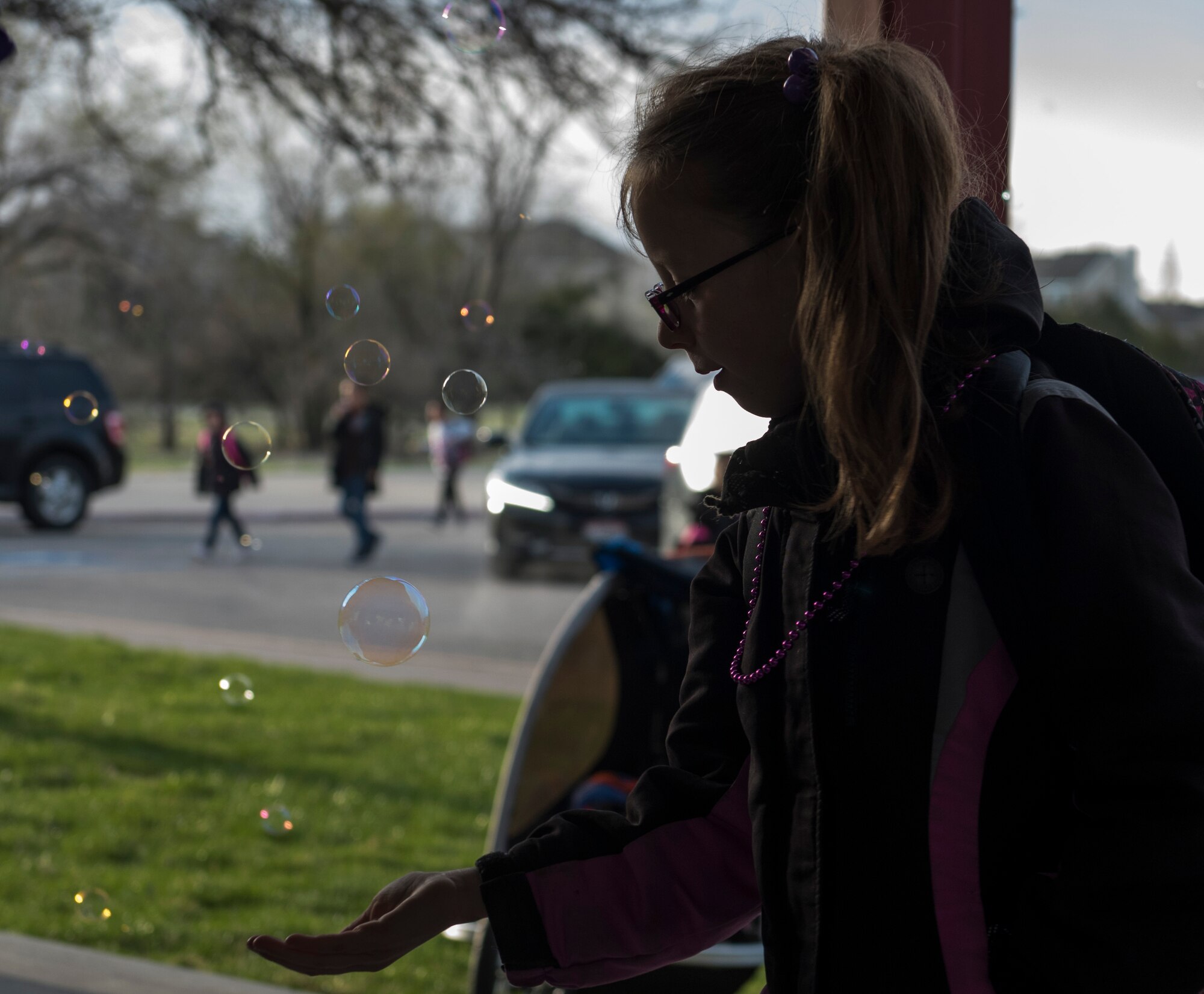 A child admires bubbles before school April 12, 2019, at Mountain Home Air Force Base, Idaho. April is the Month of the Military Child. (U.S. Air Force Photo by Airman 1st Class Hailey Bivens)