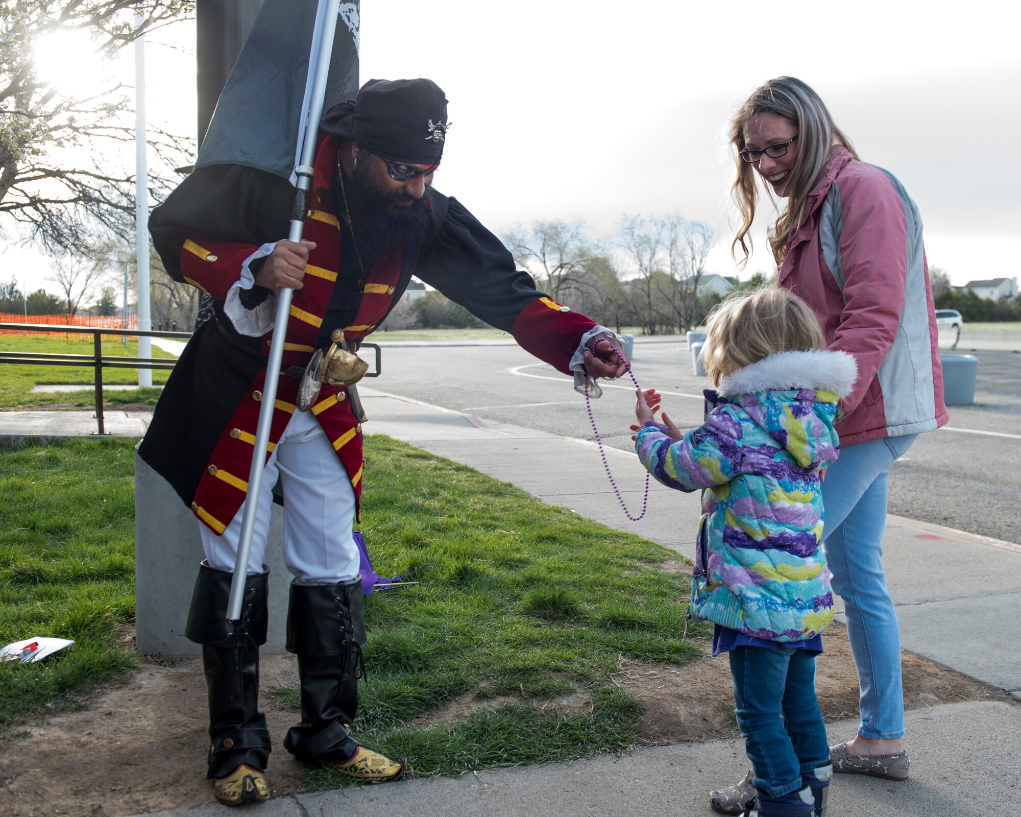 A 428th Fighter Squadron Airman gives a child a purple necklace before school begins April 12, 2019, at Mountain Home Air Force Base, Idaho. MHAFB personnel came together to show appreciation for Gunfighter kids during Month of the Military Child. (U.S. Air Force Photo by Airman 1st Class Hailey Bivens)