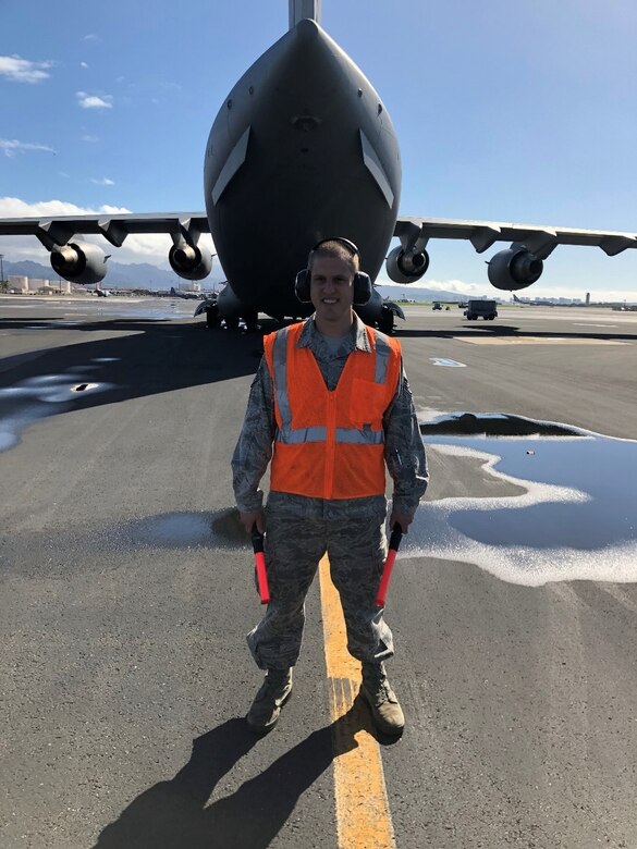 Staff Sgt. Nicholas Brown, 15th Wing Public Affairs specialist, prepares to marshal a C-17 at Hickam Field, Joint Base Pearl Harbor-Hickam, Feb. 26, 2019. SSgt Brown shadowed Tech. Sgt. Darrell Walton, 15th Aircraft Maintenance Squadron crew chief, for the day. (U.S. Air Force photo by Tech. Sgt. Darrell Walton)