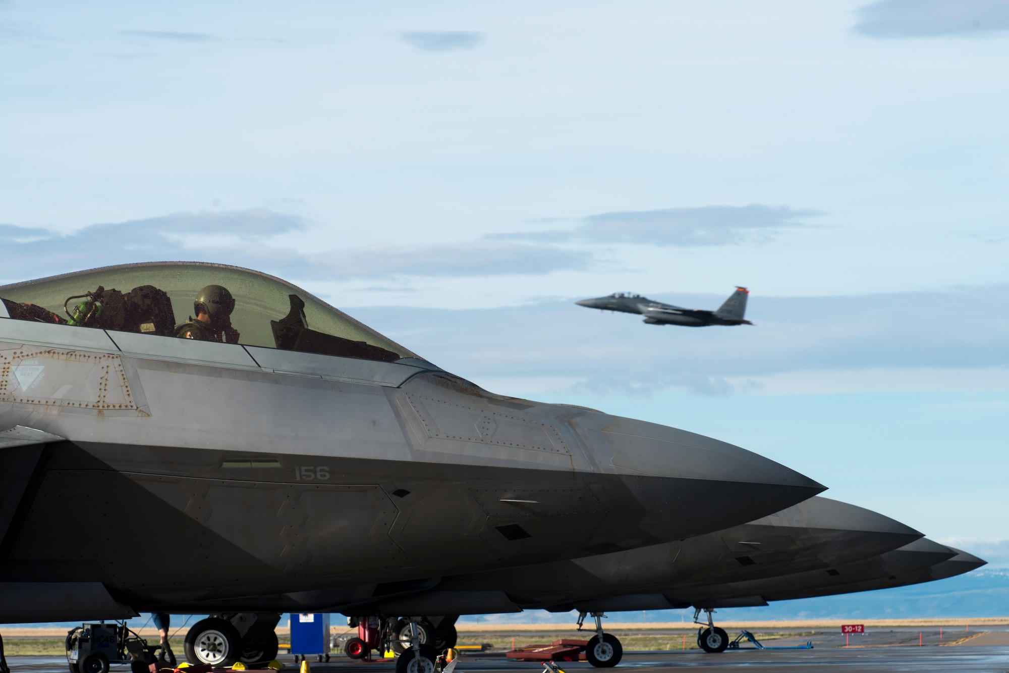 An F-15E Strike Eagle takes off behind 1st Fighter Wing F-22 Raptors stationed out of Joint Base Langley Eustis, Virginia, during Gunfighter Flag, April 5, 2019 at Mountain Home Air Force Base, Idaho. The exercise Gunfighter Flag is held once a quarter to hone skills of 366th Fighter Wing Airmen. (U.S. Air Force photo by Airman 1st Class JaNae Capuno)