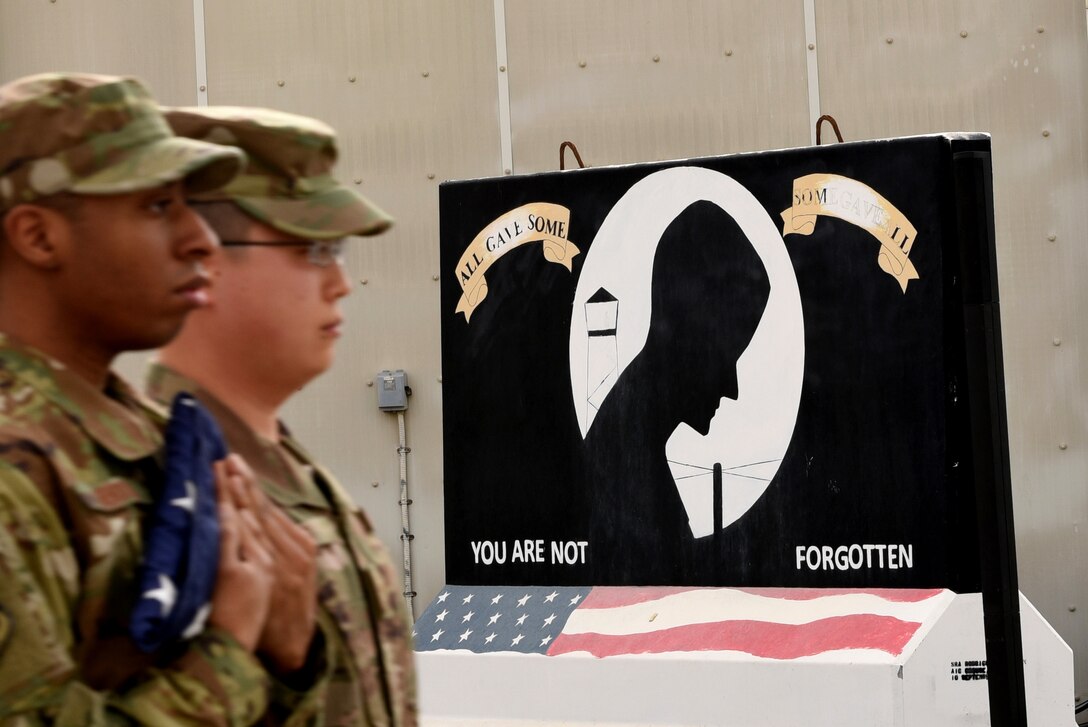 Members of the 380th Air Expeditionary Wing Honor Guard flag detail march past the POW/MIA T-wall at the conclusion of a monthly retreat ceremony on Al Dhafra Air Base, United Arab Emirates, April 5, 2019.