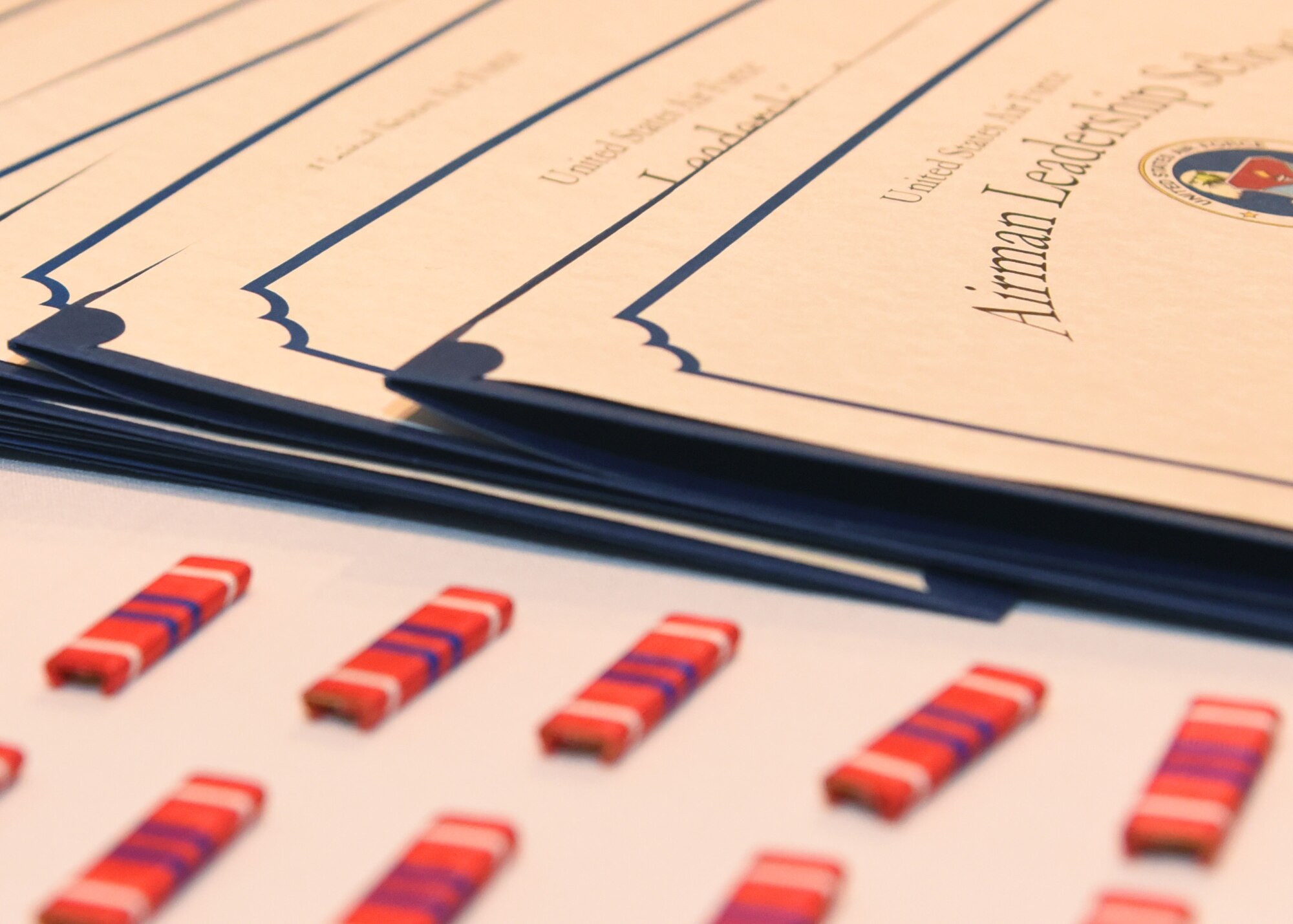 Airman Leadership School graduate certificates and ribbons are displayed during the ALS Graduation Ceremony in the Event Center at Goodfellow Air Force Base, Texas, April 11, 2019. ALS is a six week course to develop Senior Airman into effective leaders at the Staff Sergeant level. (U.S. Air Force Photo by Airman 1st Class Abbey Rieves/Released)