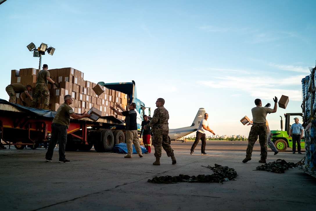Service members unload boxes from a large truck.