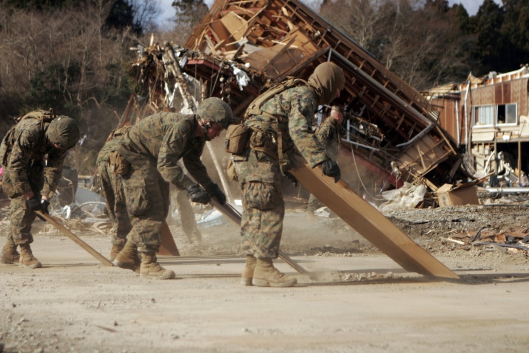 Marines clear debris off a road.