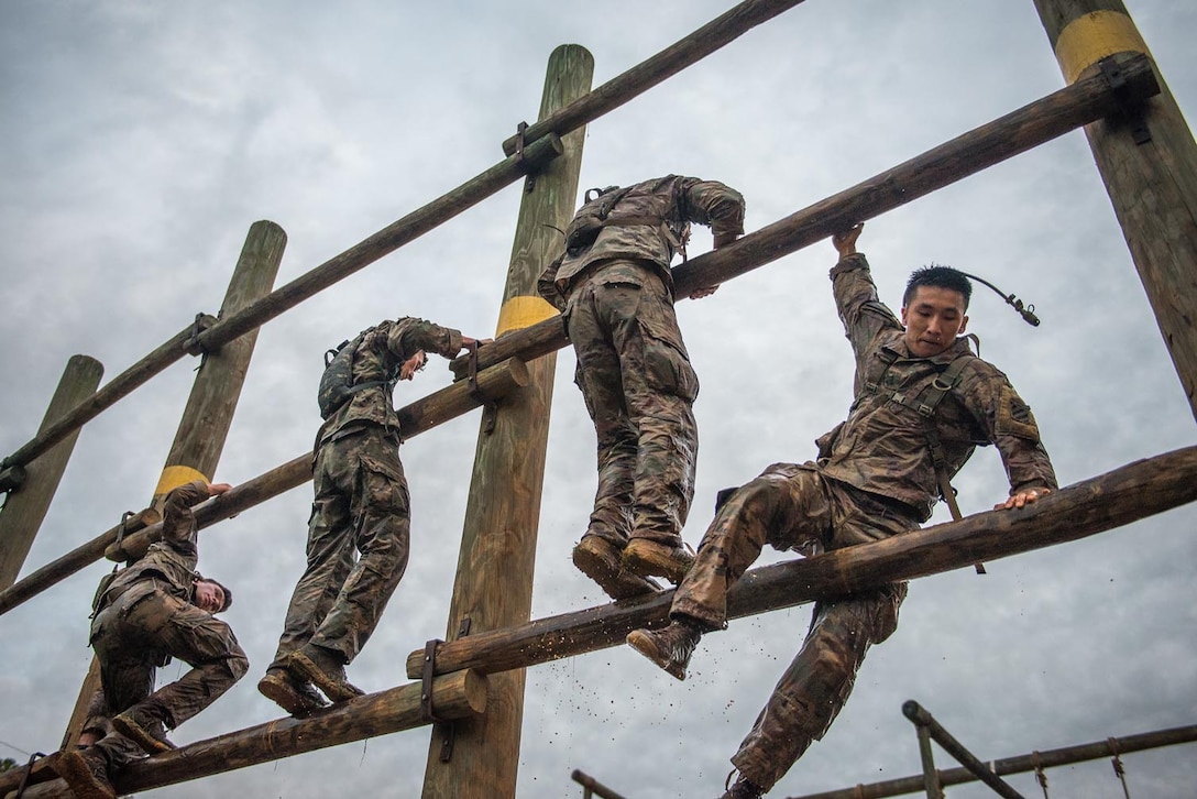 Four soldiers climb on a wide wooden ladder.